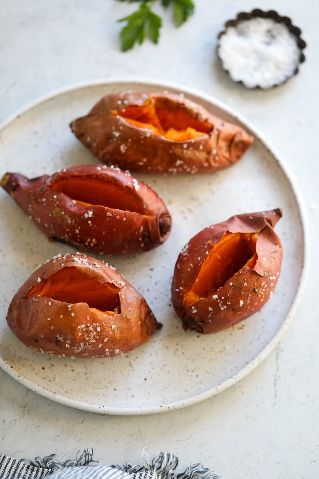 Overhead view baked sweet potatoes on platter, middle of sweet potatoes cut open to show fluffy insides