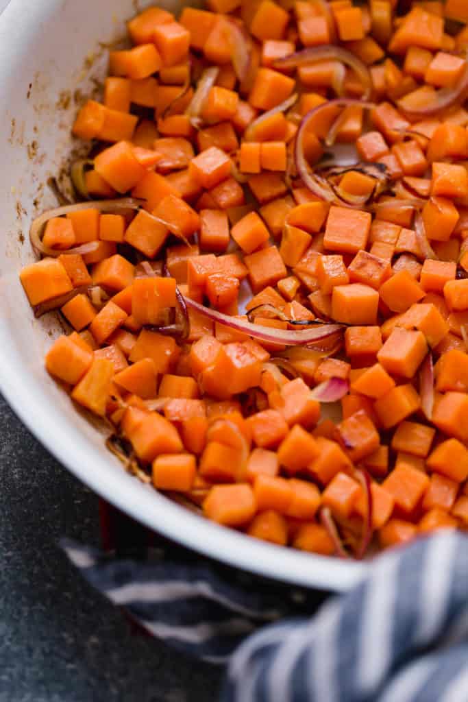 Diced sweet potatoes cooked in casserole dish with purple onions