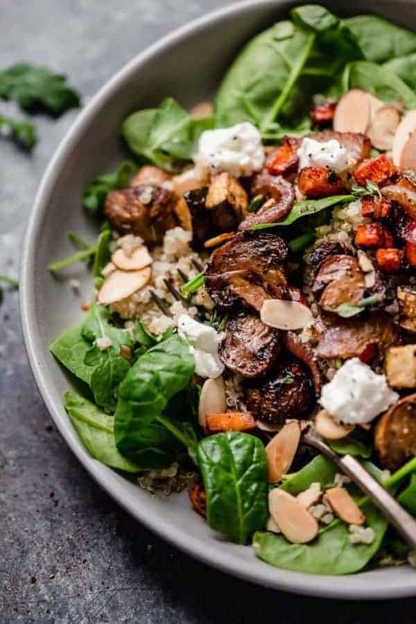 Overhead photo of the Balsamic Roasted Vegetables with Quinoa Salad served over greens and topped with toasted almonds and goat cheese. 