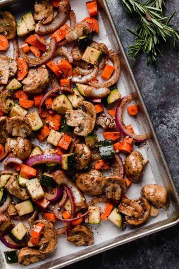 A sheet pan of a variety vegetables prepped for roasting for the Balsamic Roasted Vegetable with Quinoa Salad. Overhead shot.