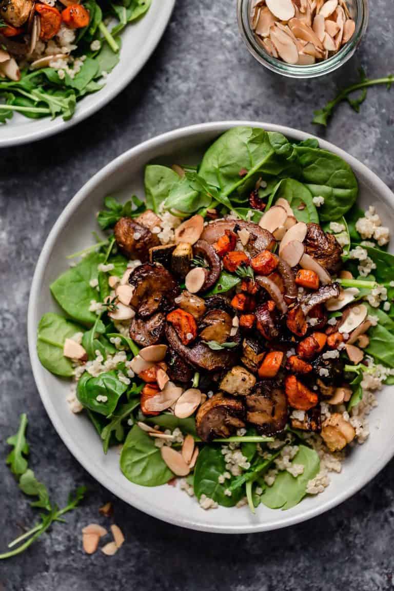 Overhead view of a plate filled with Balsamic Roasted Vegetables with Quinoa on top of a bed of spinach.