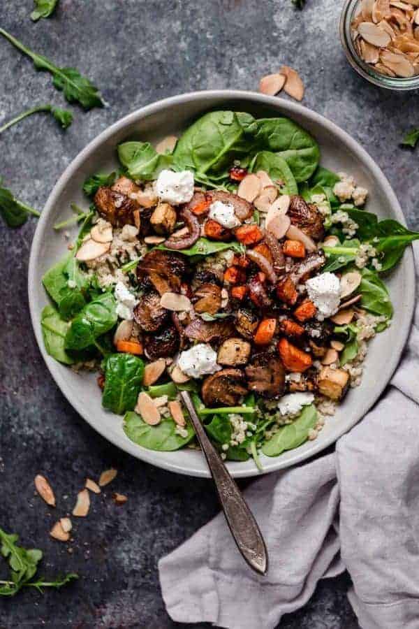 Overhead photo of the Balsamic Roasted Vegetables with Quinoa Salad served over greens and topped with toasted almonds and goat cheese. 