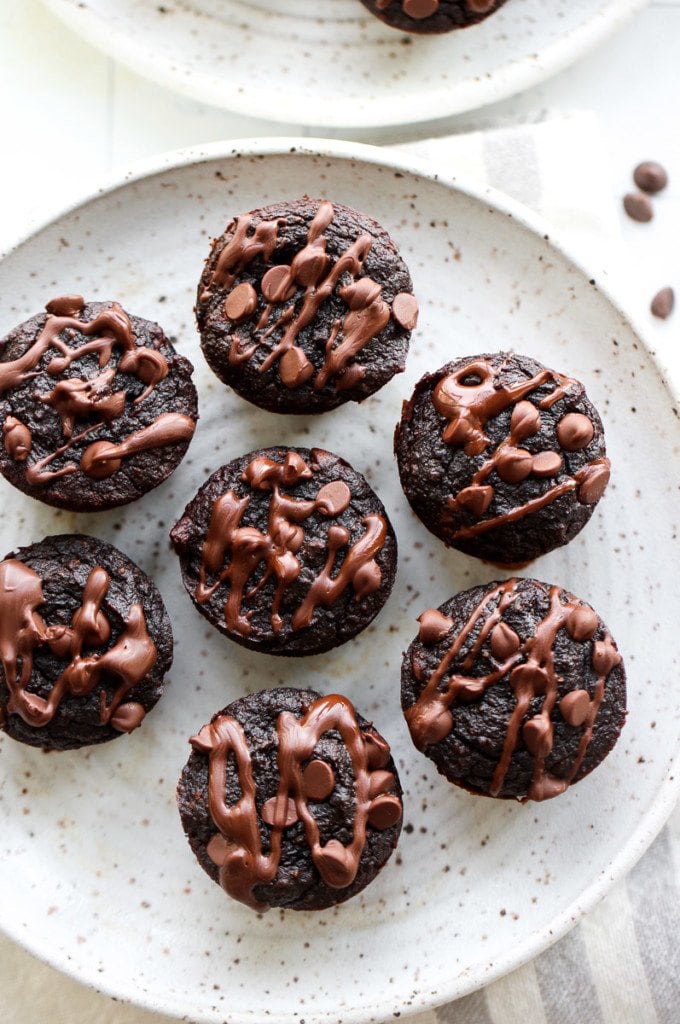Overhead view of a plate filled with grain-free sweet potato avocado brownie bites, topped with mini chocolate chips and chocolate drizzle.