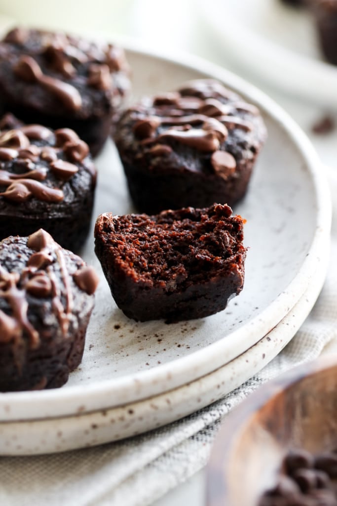 Close up view of several grain-free sweet potato avocado brownie bites on a speckled plate, one brownie bite with a bite taken out to show cake-like texture.