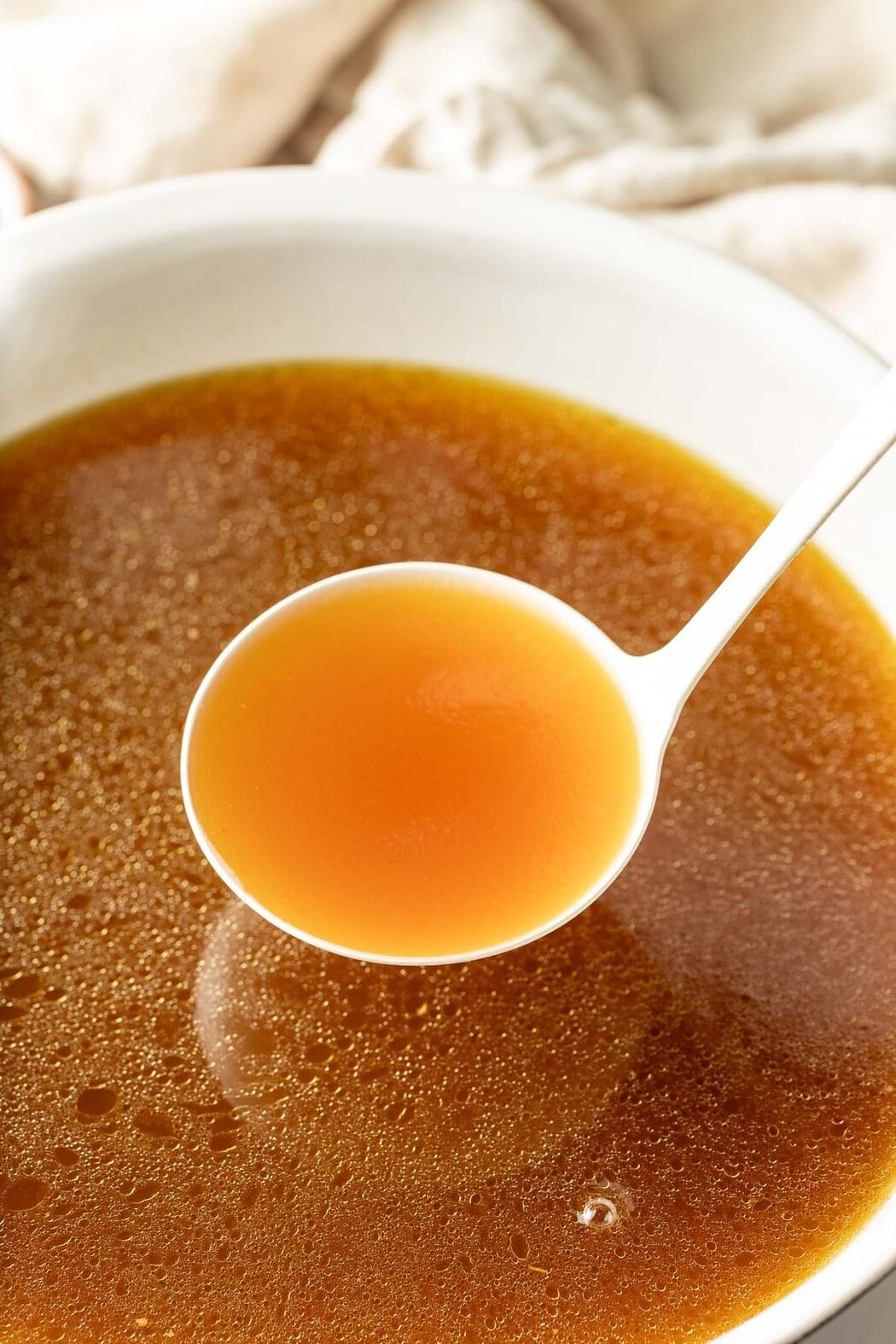 Close up view a spoon scooping a spoonful of homemade bone broth.