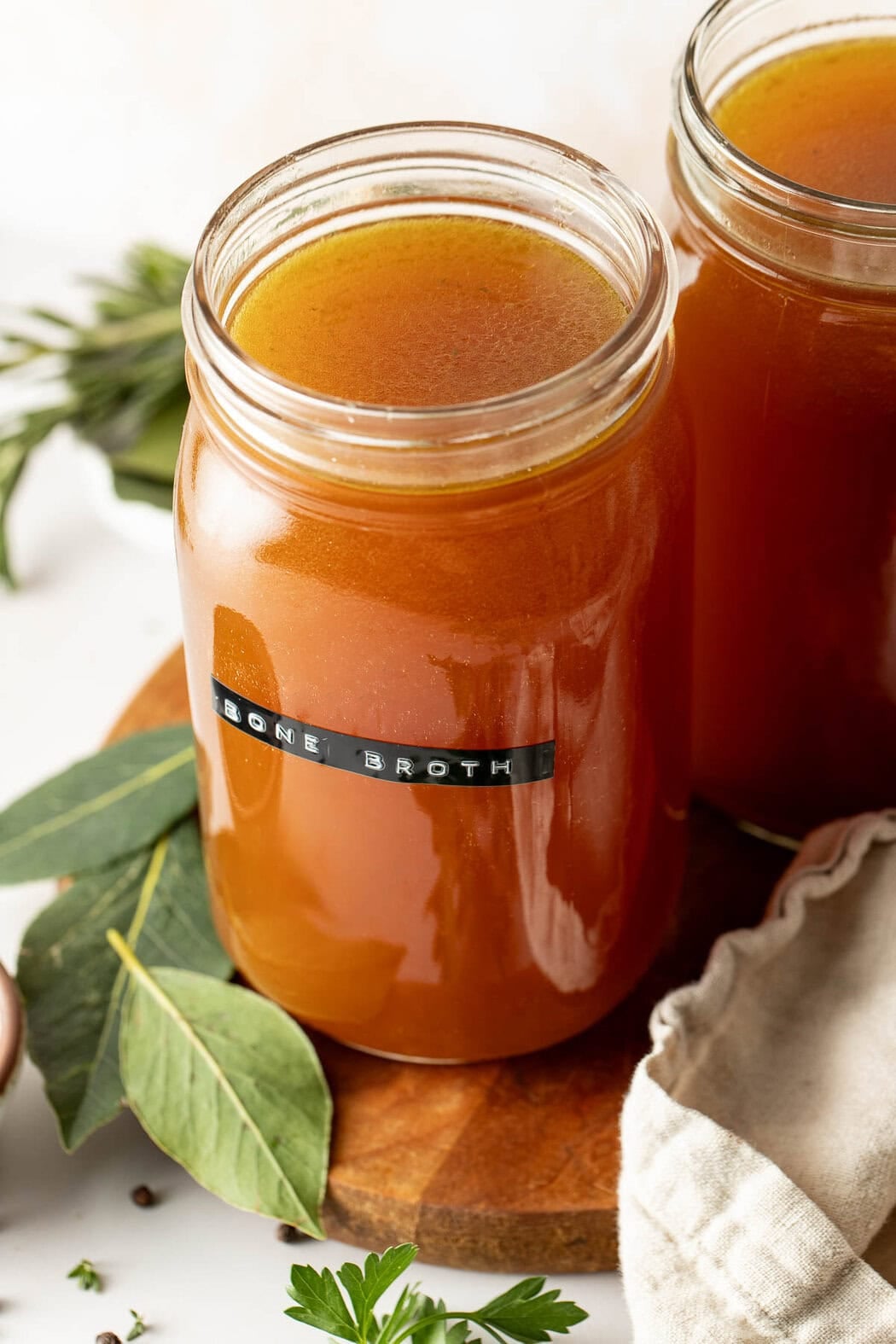 Close up view of two mason jars filled with homemade bone broth labeled with a black label on the front of the jar.
