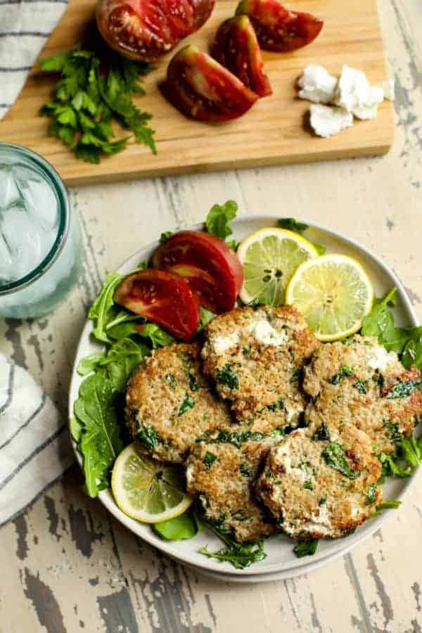 Aerial view of Quinoa Spinach Turkey Burgers with Goat Cheese on a plate with tomato wedges and lemon slices