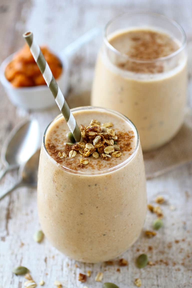 Close up view of two pumpkin pie protein smoothies topped with spices and oats and packed with protein and healthy fats. 