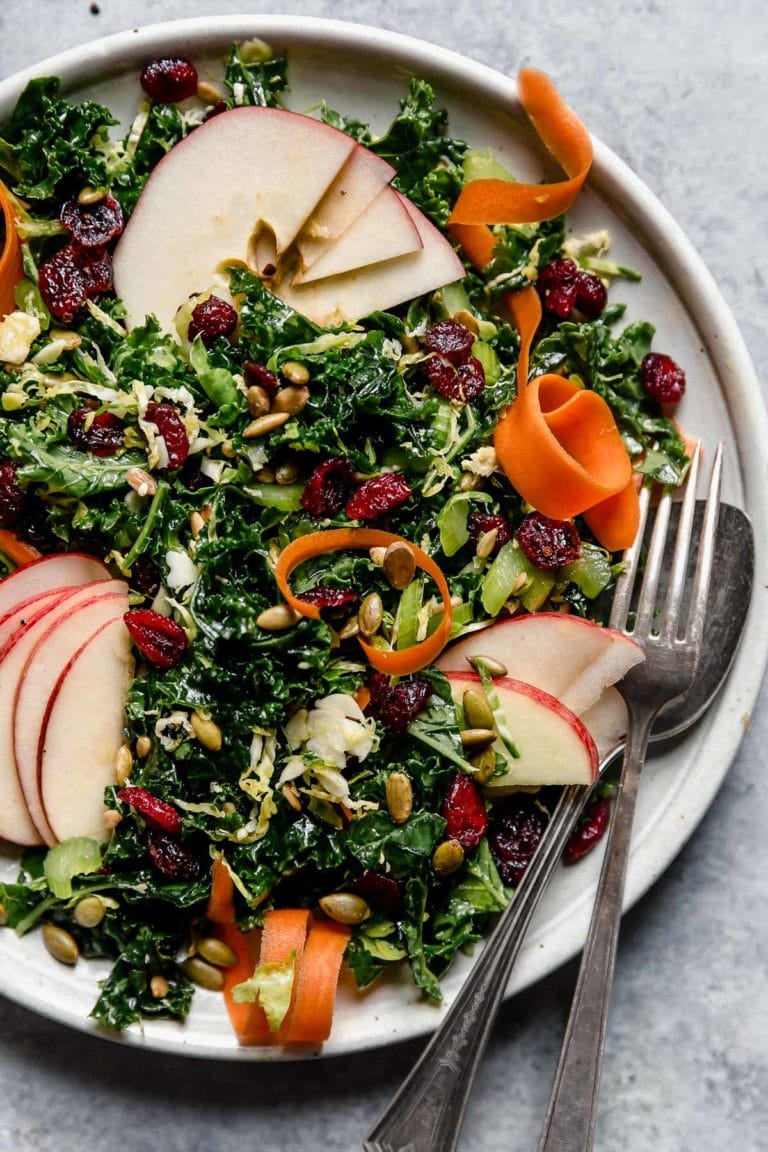 Massaged kale salad on a plate with a fork on the side.