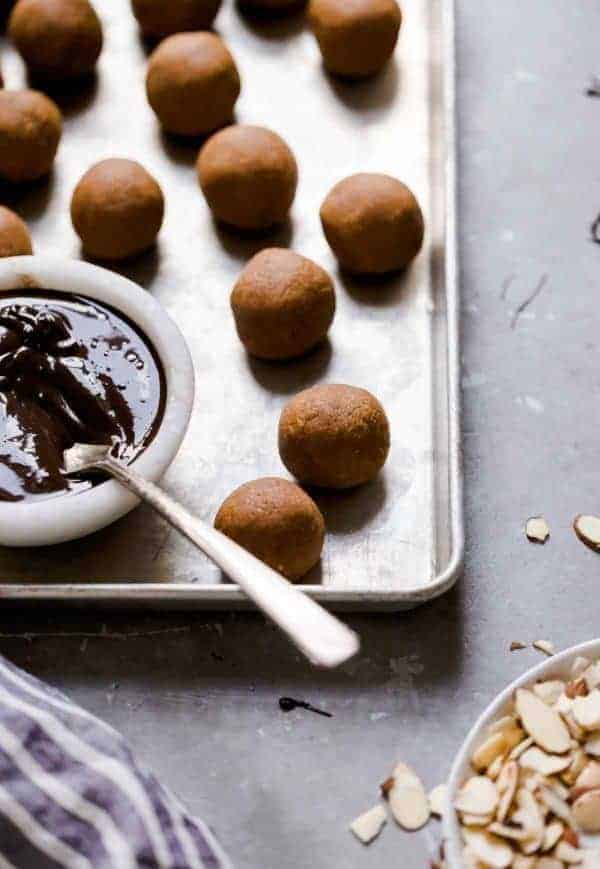 Pumpkin Pie Truffle inside balls lined on a cookie sheet with a bowl of chocolate and spoon to cover the truffle balls