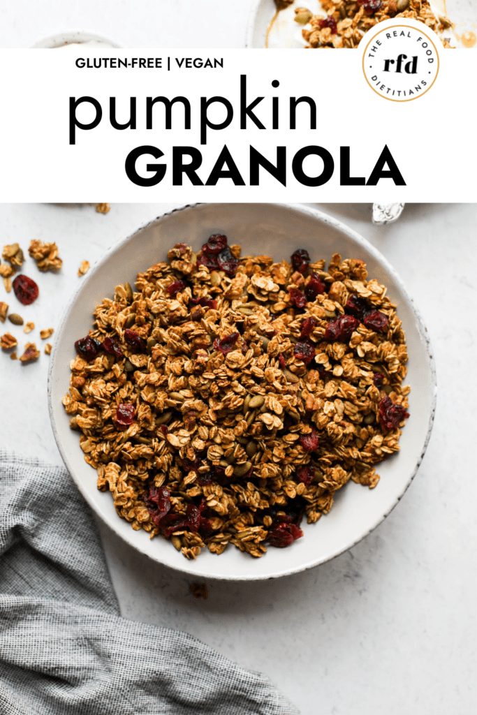 Overhead view of pumpkin granola with dried cranberries and chopped pecans in a white bowl.