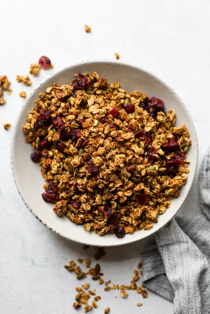 Pumpkin granola with dried cranberries and pecans in a white serving bowl