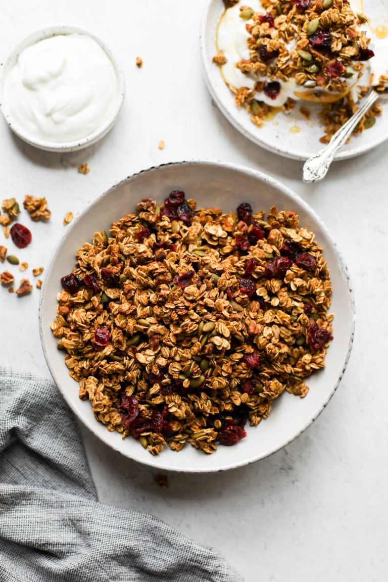 A bowl of pumpkin spice granola studded with dried cranberries and crunchy nuts and seeds. 