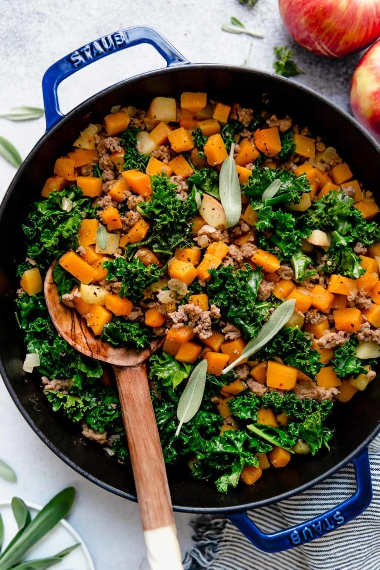 Squash, Apple, and Sausage Hash in a blue pan topped with fresh sage leaves. 