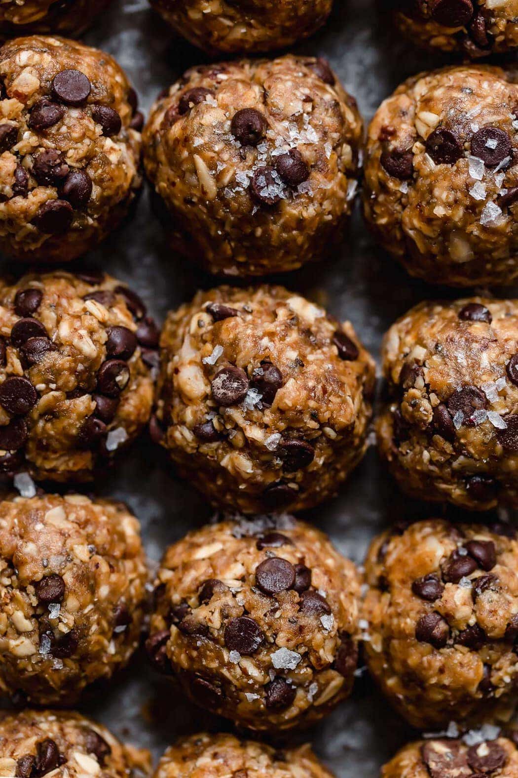 Peanut Butter Oatmeal Balls lined packed tightly in rows. Topped with flakes of sea salt.