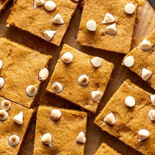 Overhead view pumpkin blondies topped with white chocolate chips cut into squares