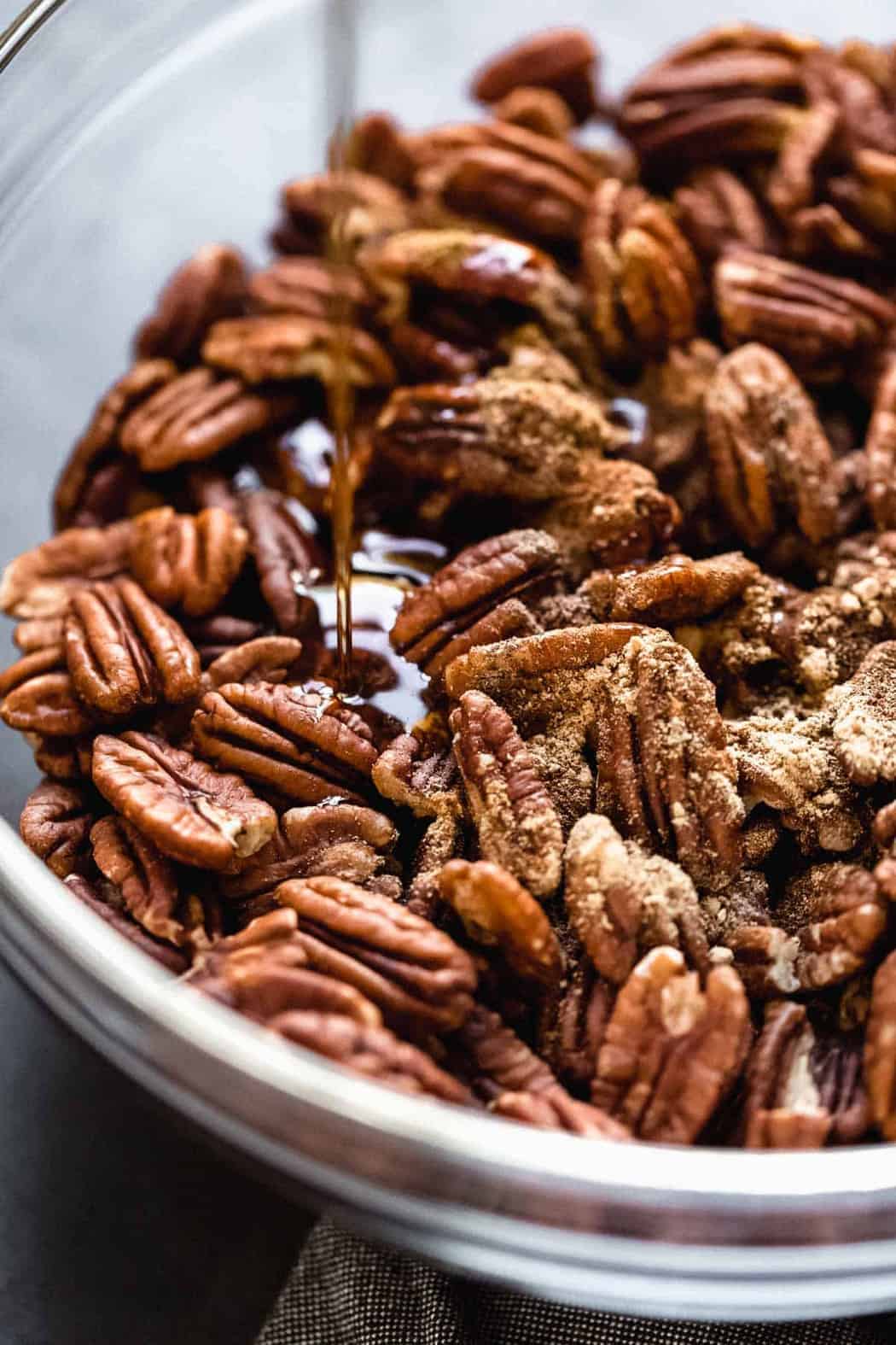 Pecans with maple syrup drizzled on top ready for baking
