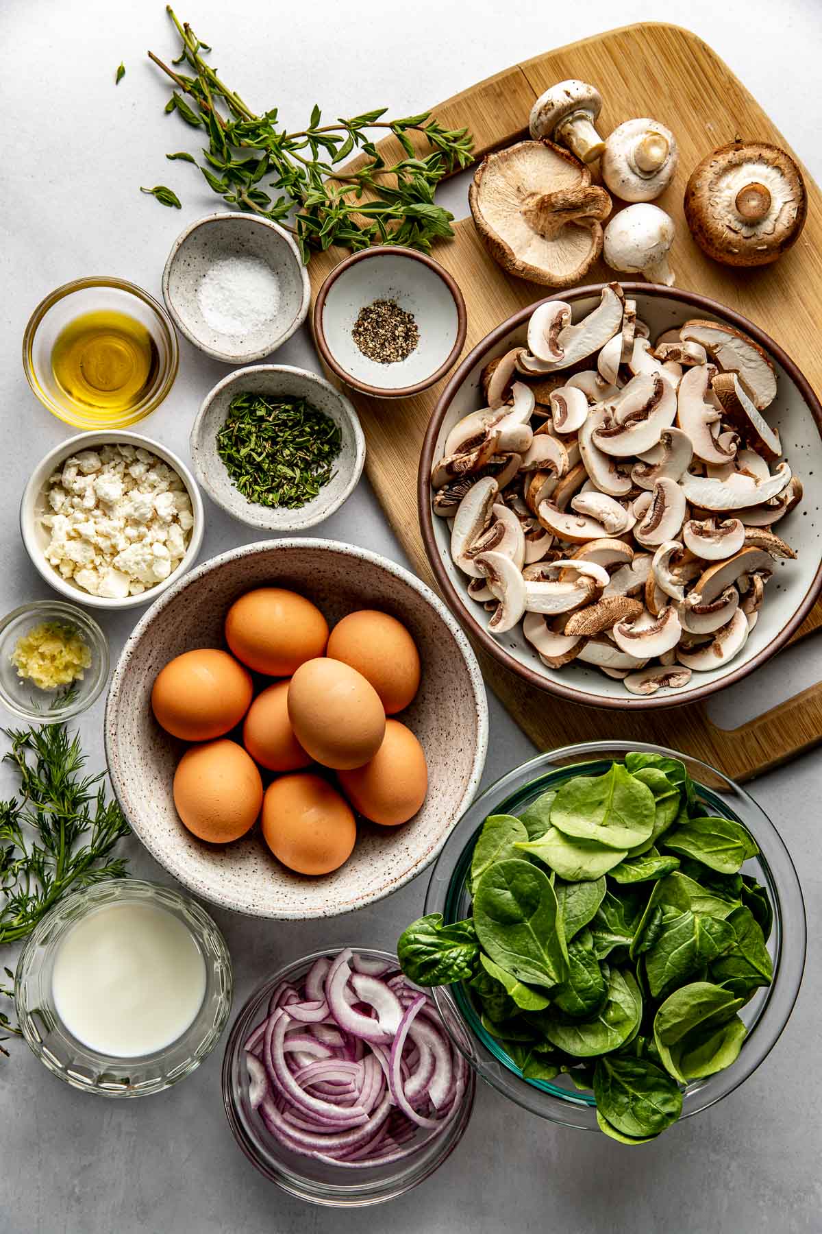 Overhead view of a variety of ingredients for Mushroom Frittata in different sized bowls. 