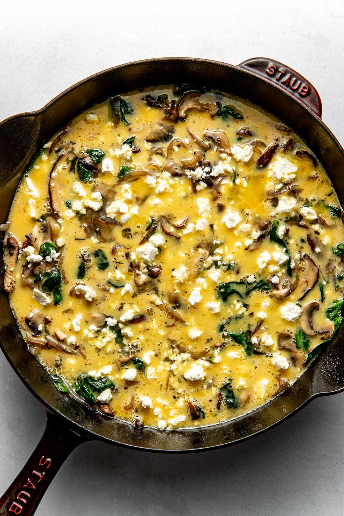 Overhead view of a pan filled with Mushroom Frittata ingredients ready for baking. 