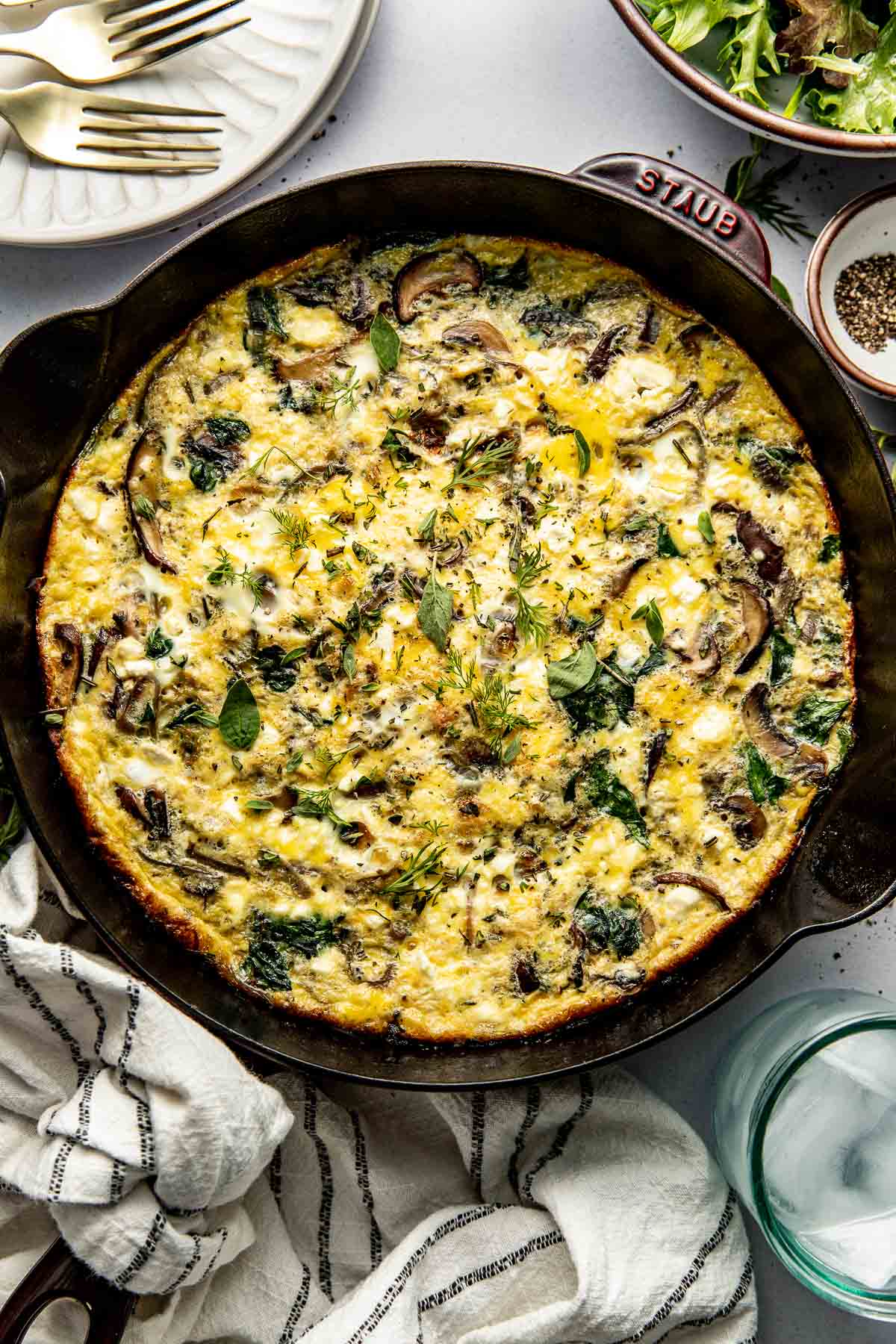 Overhead view of a freshly baked pan of Mushroom Frittata with Feta topped with dill. 