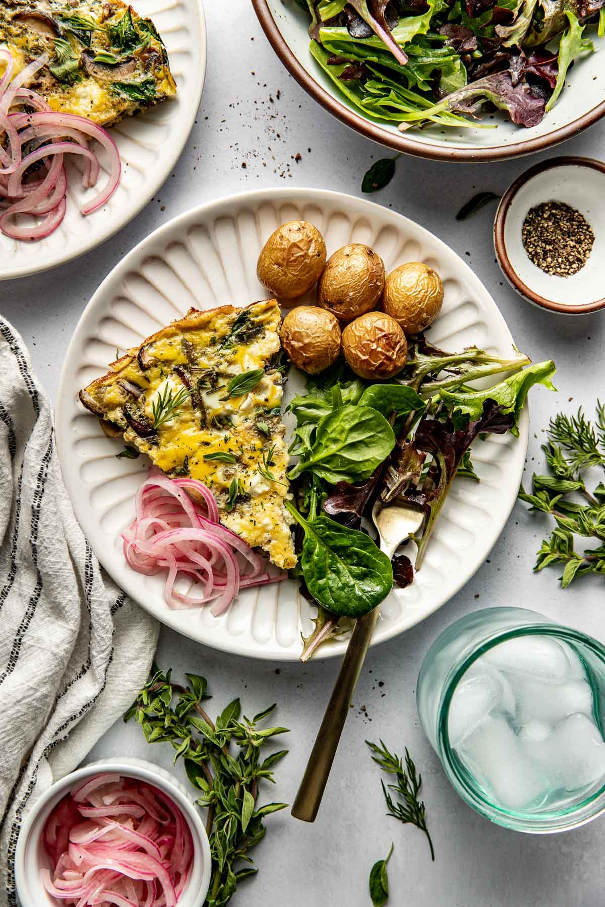 Overhead view of a plate of Mushroom Frittata with Feta, greens and roasted potatoes. 