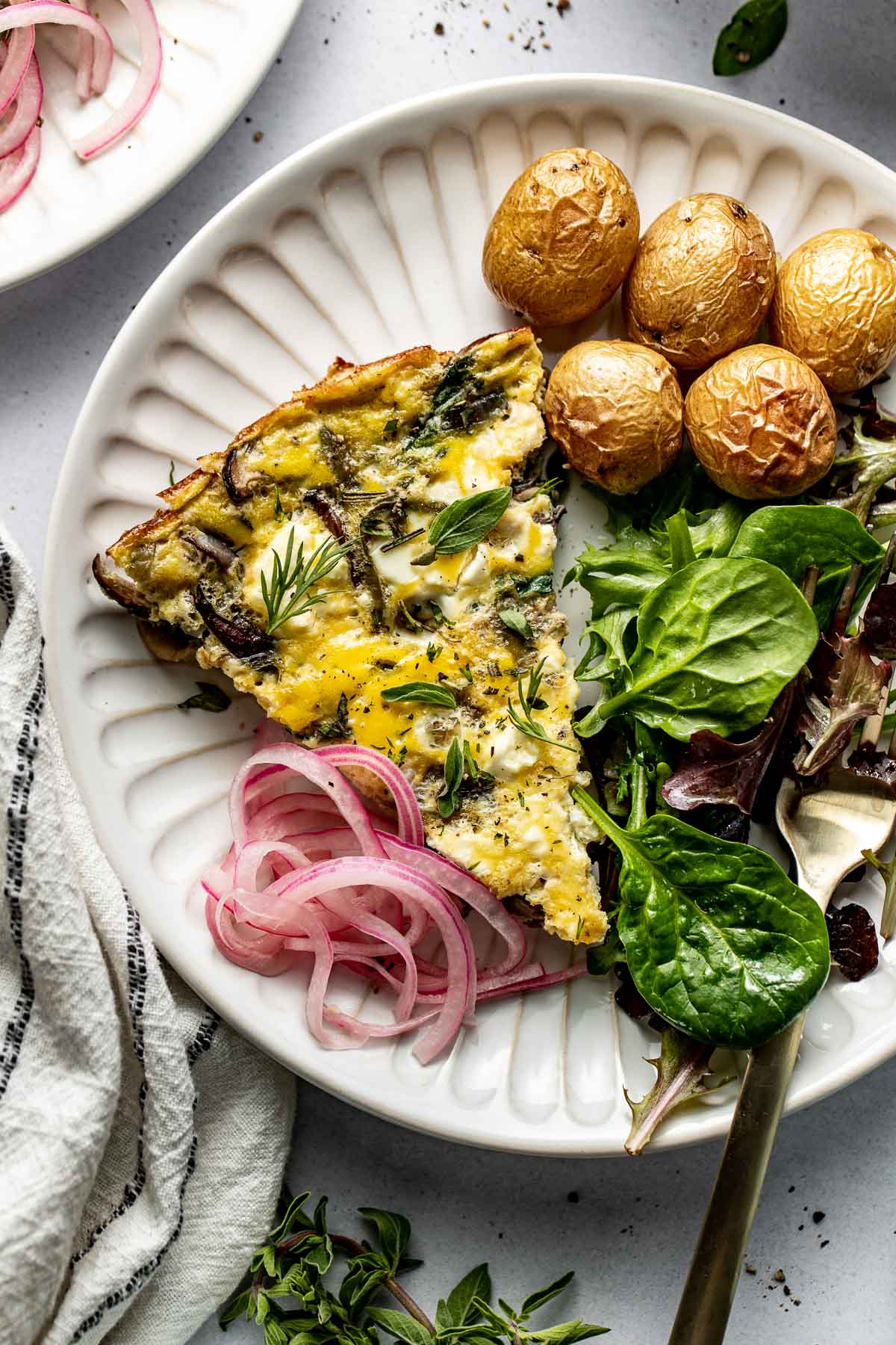 Overhead view of a plate of Mushroom Frittata with Feta and a side of roasted potatoes. 