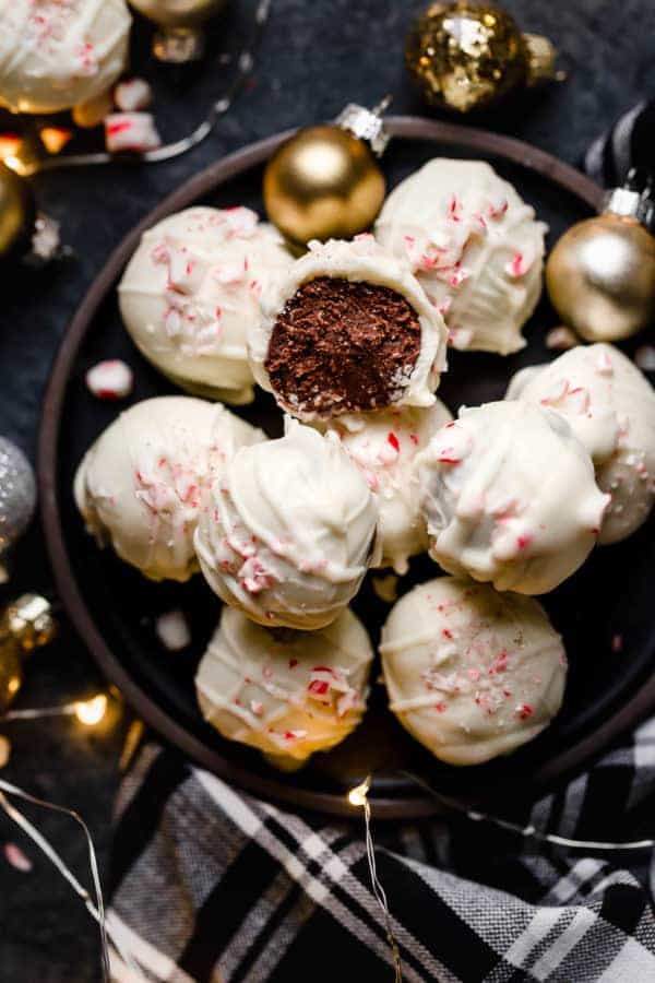 Overhead view of Peppermint Brownie Batter Truffles on a brown platter with one missing a bite