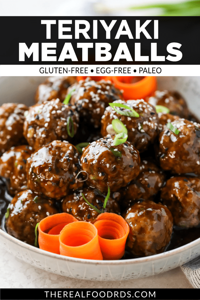 Teriyaki meatballs coated in homemade teriyaki sauce in a white serving bowl topped with sesame seeds, scallions, and swirled carrot shavings.