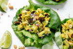 Curry chicken salad in lettuce leaves topped with raisins and cashews.