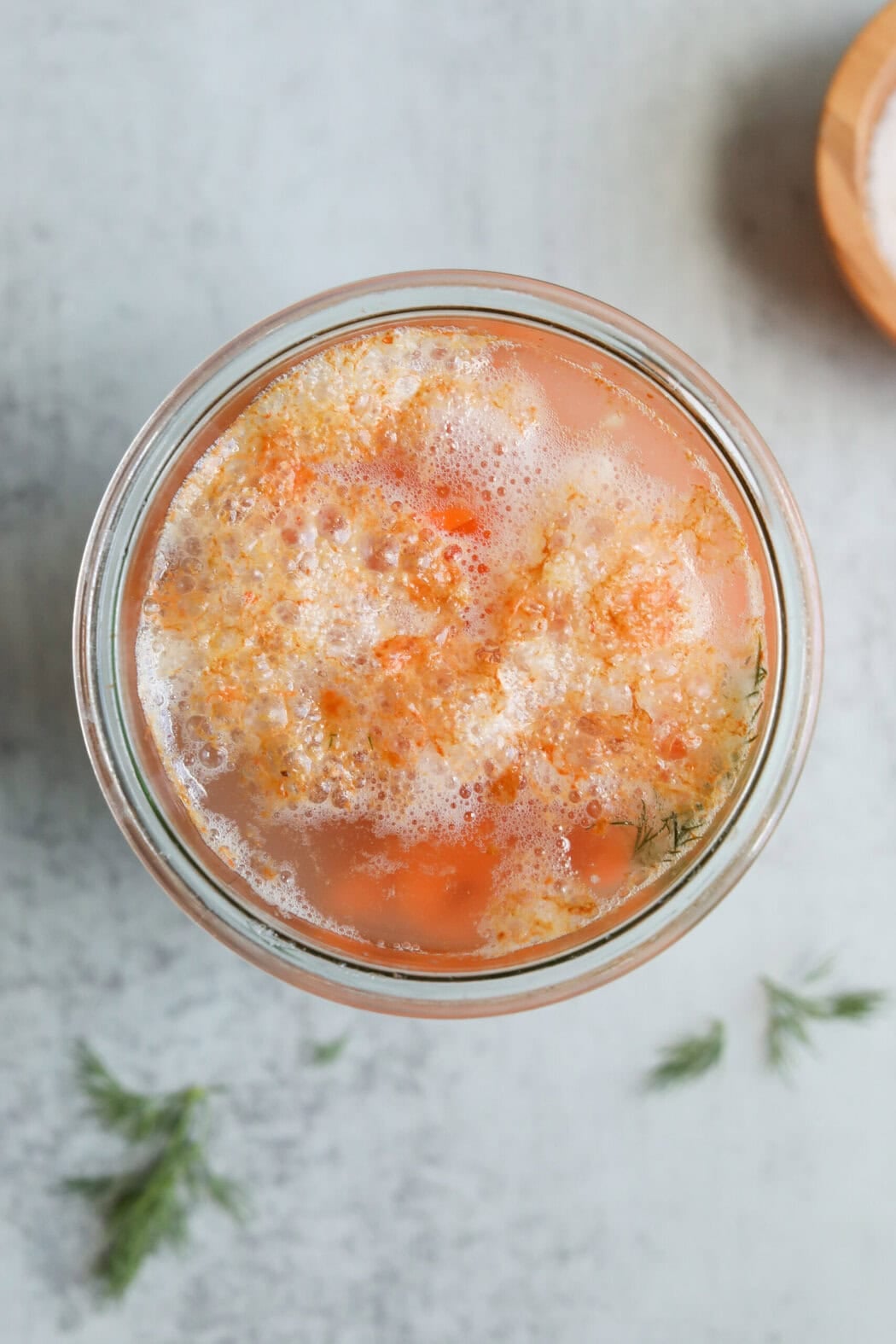 A jar of fermented carrots with scum on top. 