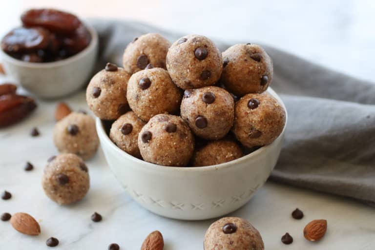White bowl filled with almond butter energy balls with mini chocolate chips.
