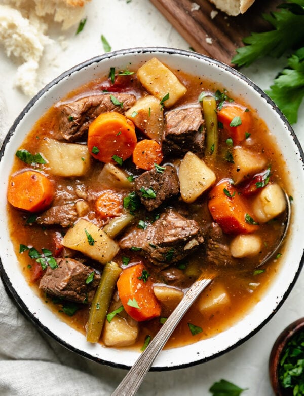 Overhead view rustic white bowl filled with slow cooker beef stew with root vegetables