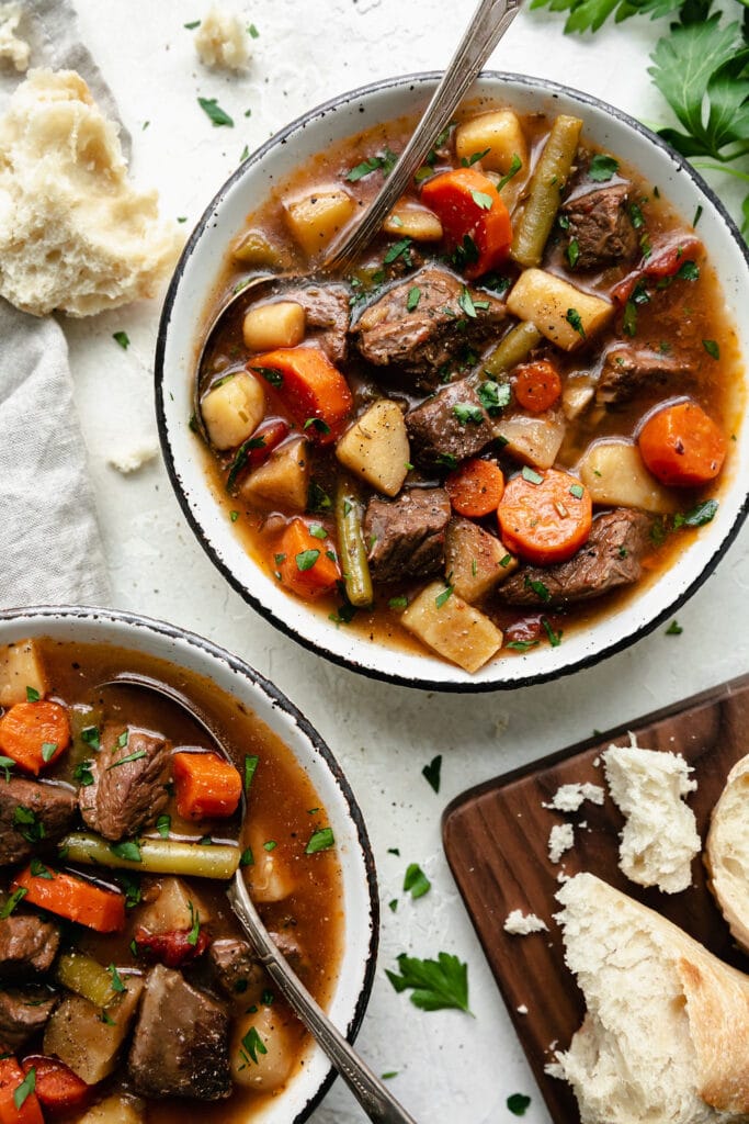 A rustic bowl filled with slow cooker beef stew with potatoes, parsnips, and green beans.