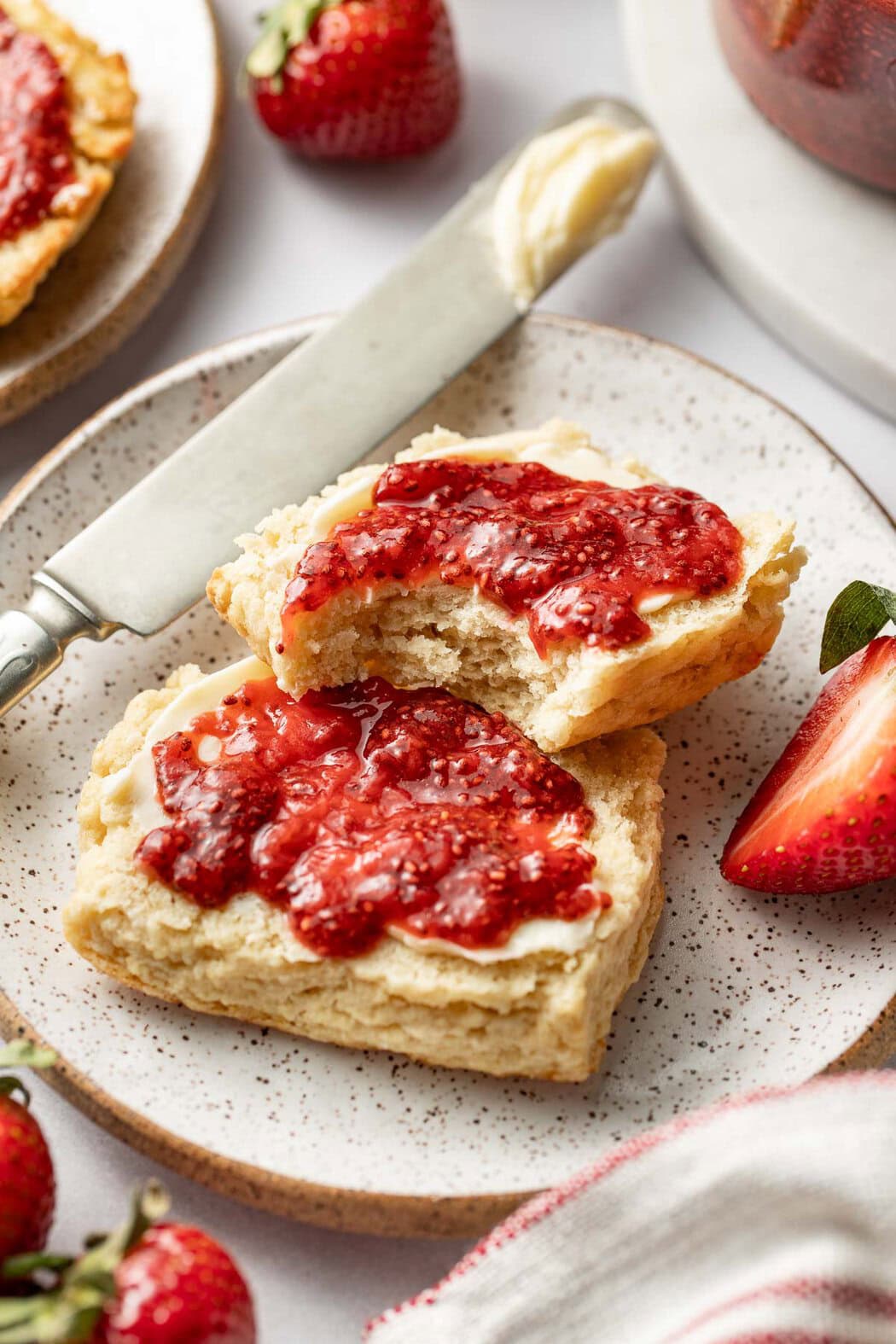Overhead view of a biscuit sliced in half with butter and strawberry Chia Seed Jam smeared on top.