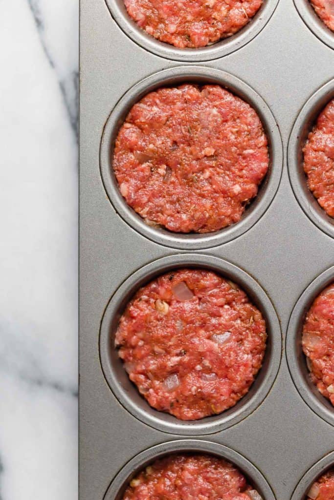 Close up view of ground beef pressed into a muffin tin for mini meatloaf muffins.