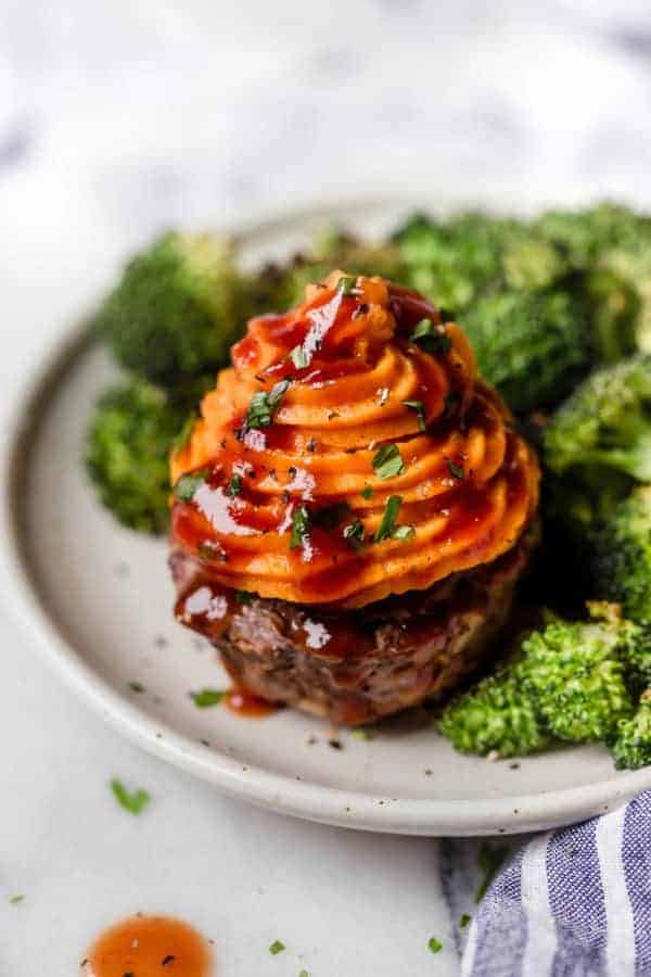 Overhead view of BBQ Meatloaf Muffins with Sweet Potato Topping and a side of broccoli on a white plate