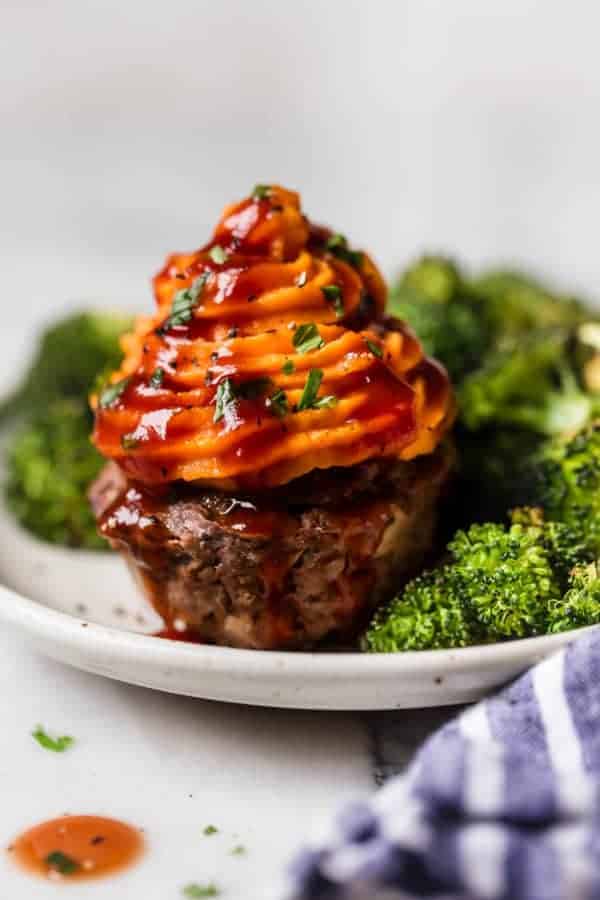 BBQ Meatloaf Muffins with Sweet Potato Toppping with a side of broccolli on a white plate 