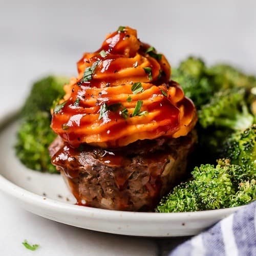 A plate with a BBQ Meatloaf Muffin with Sweet Potato Topping on it next to roasted vegetables