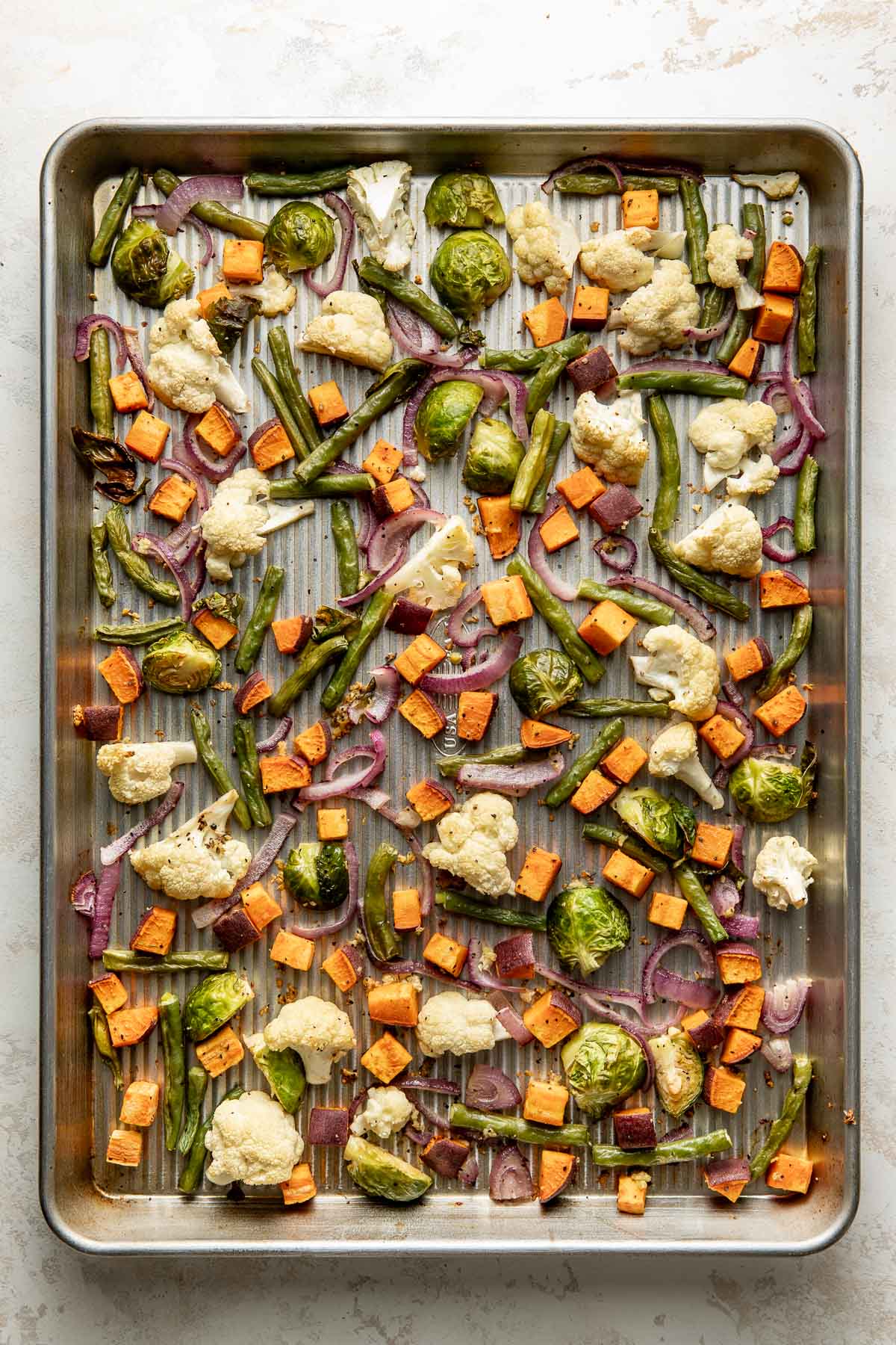 Roasted mixed vegetables on a sheet pan.