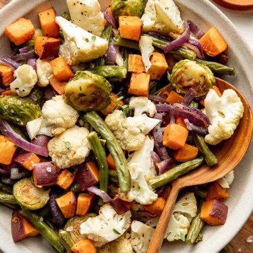 A bowl of roasted vegetables, a wooden spoon sticking out.