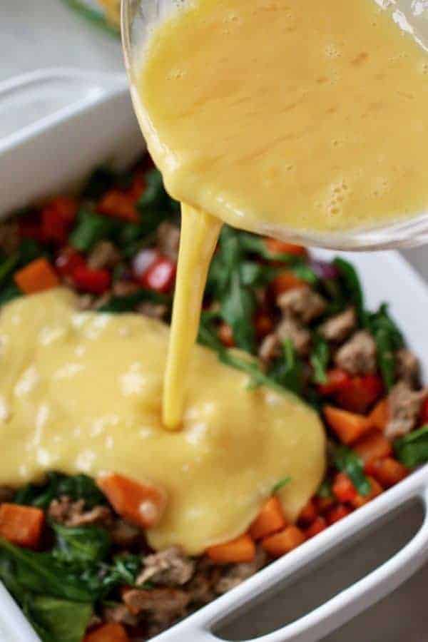 Photos of whisked eggs being poured in a white square baking dish that has the remaining Turkey Sausage Sweet Potato Egg Bake ingredients in it.