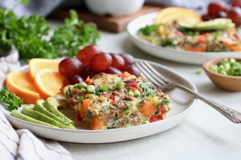 Serving of sweet potato turkey sausage egg bake on white plate with grapes