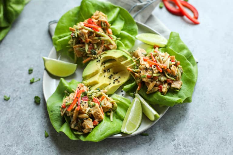 Plate of three Asian chicken salad lettuce wraps on butter lettuce ready to eat. 
