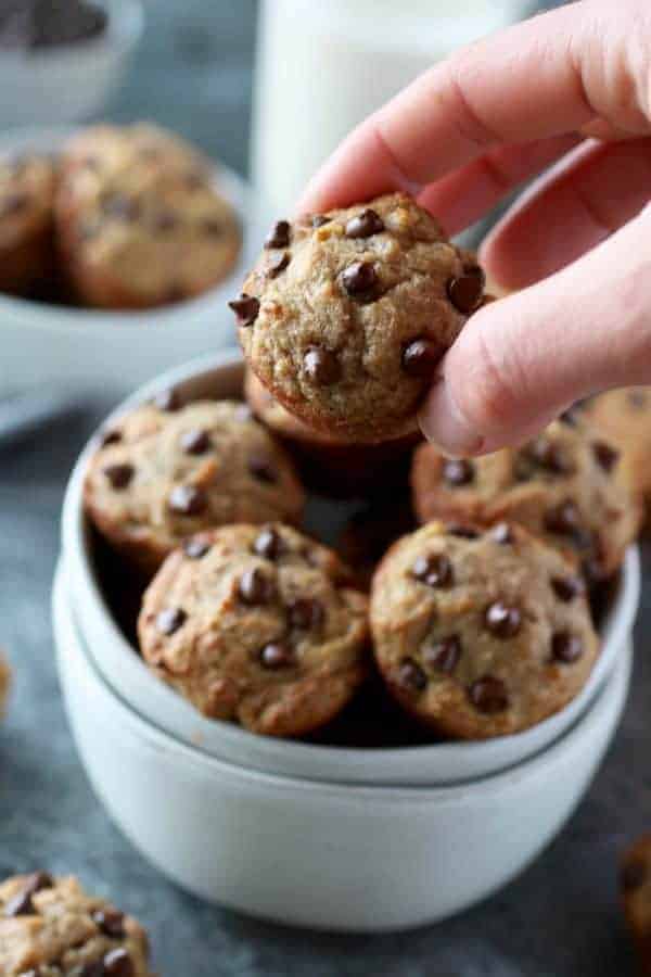 Grain-Free Banana Chocolate Chip Mini Muffins with a hand grabbing a muffin out of a white bowl
