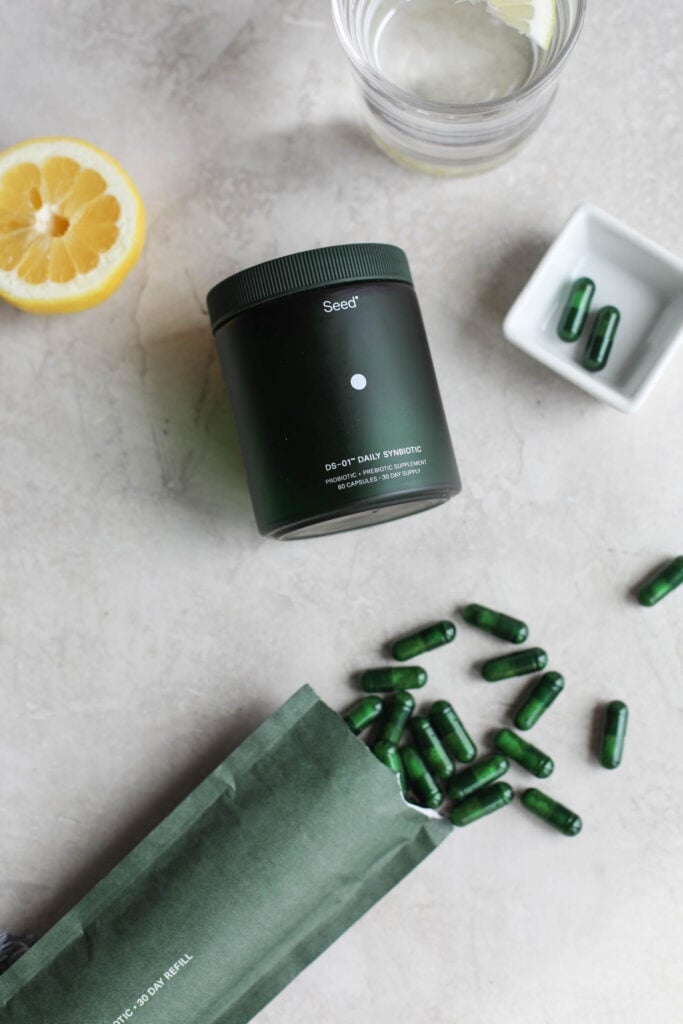 Overhead view Seed probiotic canister on counter with capsules scattered around.