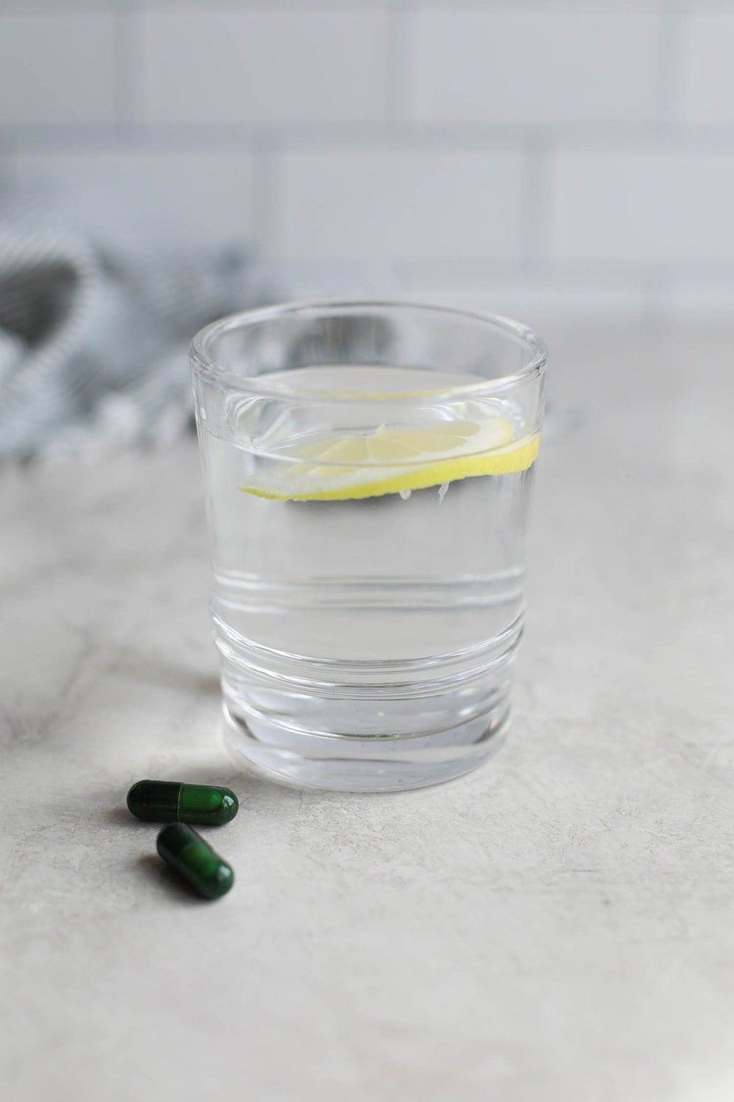 A glass of lemon water with 2 probiotic tablets