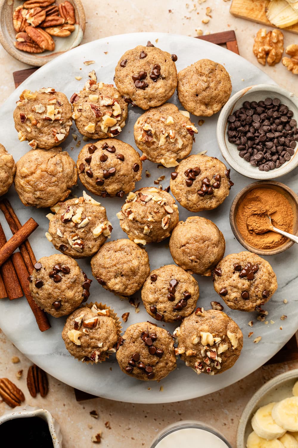 Overhead view of a plate filled with Mini Banana Muffins topped with chocolate chips and pecan pieces. 