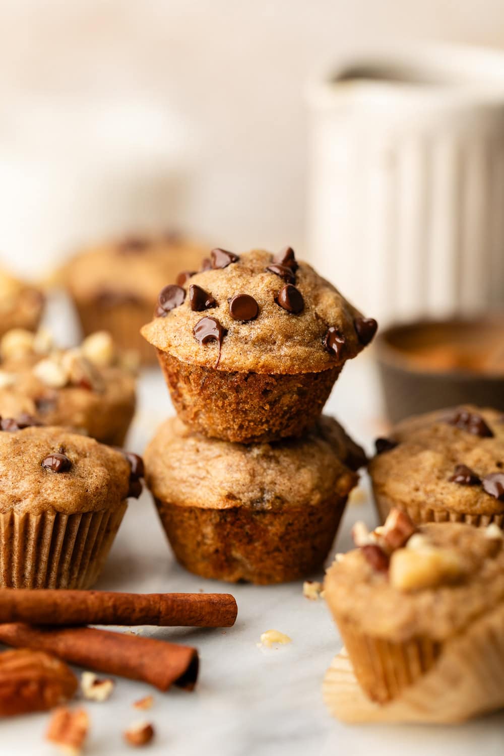 Close up view of 2 Mini Banana Muffins stacked on top of each other topped with chocolate chips. 