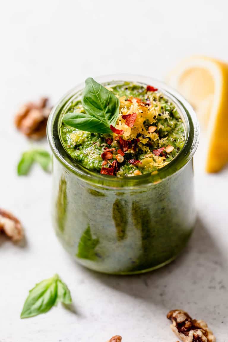 Basil walnut pesto in a small jar topped with lemon zest and red pepper flakes