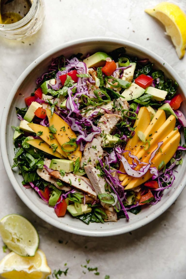 A bowl of mango chicken salad with avocado topped with a lemon-lime vinaigrette. 